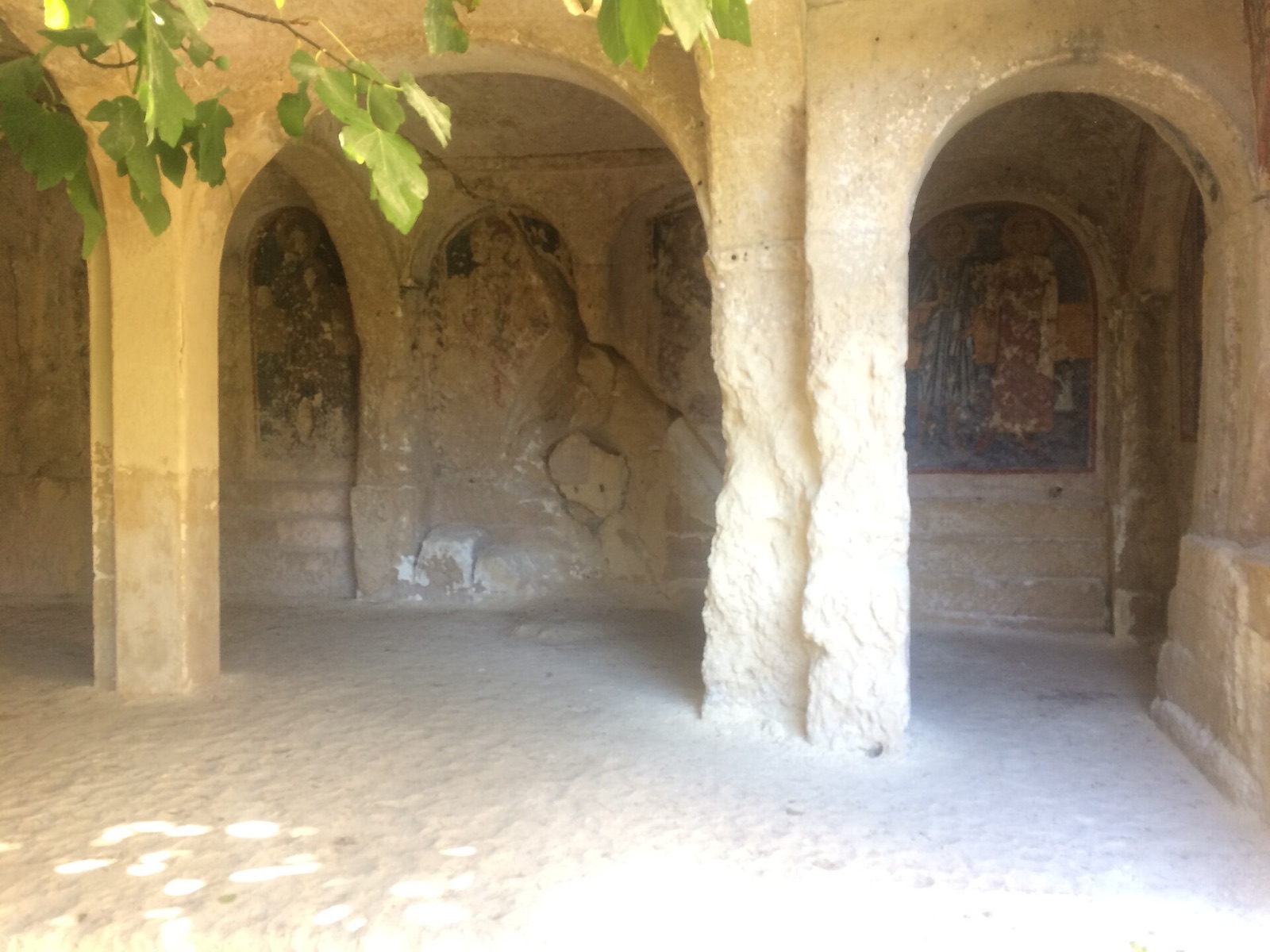 Interno di una cripta rupestre di Massafra con archi scavati nella roccia e affreschi